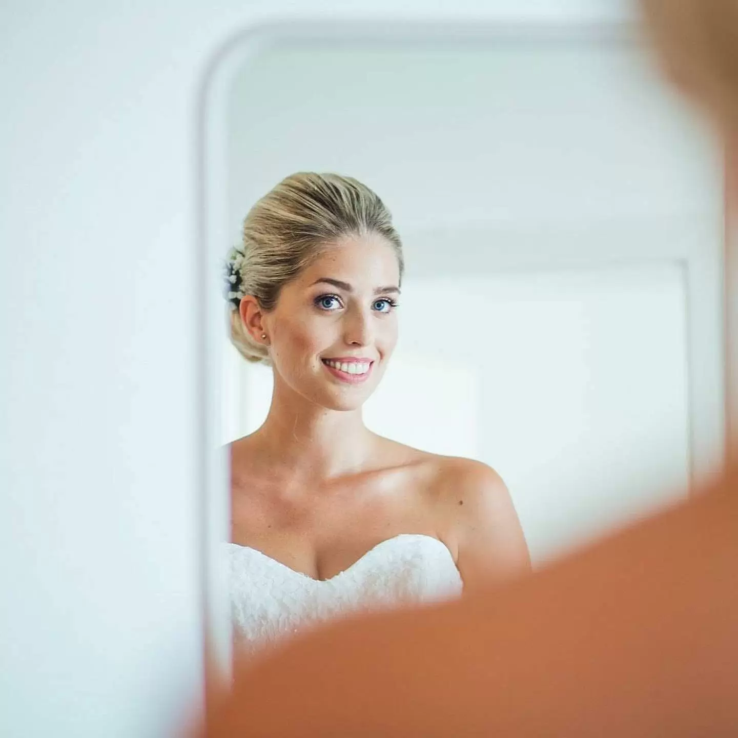 Фото. Невеста смотрит на свой образ через зеркало смартфона.