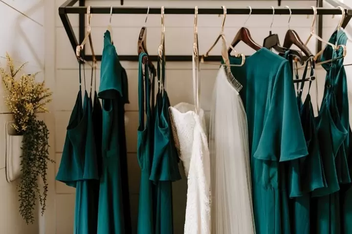 На вешалке висят платья для подружек невесты в цвете 2022 года Синяя гавань (Harbour Blue)