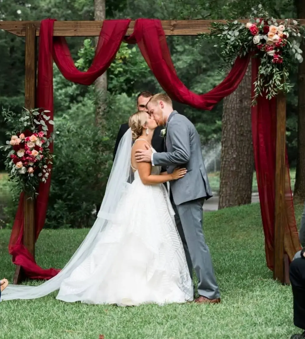 Фото. Жених и невеста целуются на фоне свадебной арки