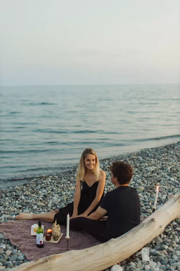Девушка и молодой человек на пикнике около моря