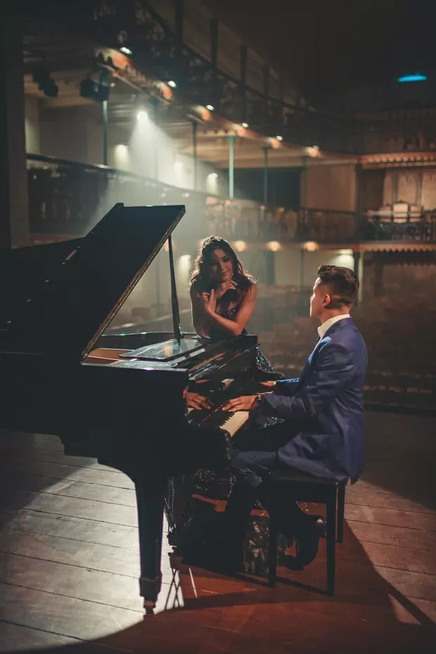 Мужчина играет на рояле, а девушка слушает его
